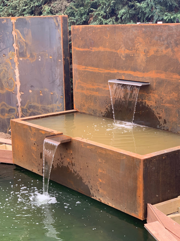 free standing corten steel pond wall next to pond filled with water