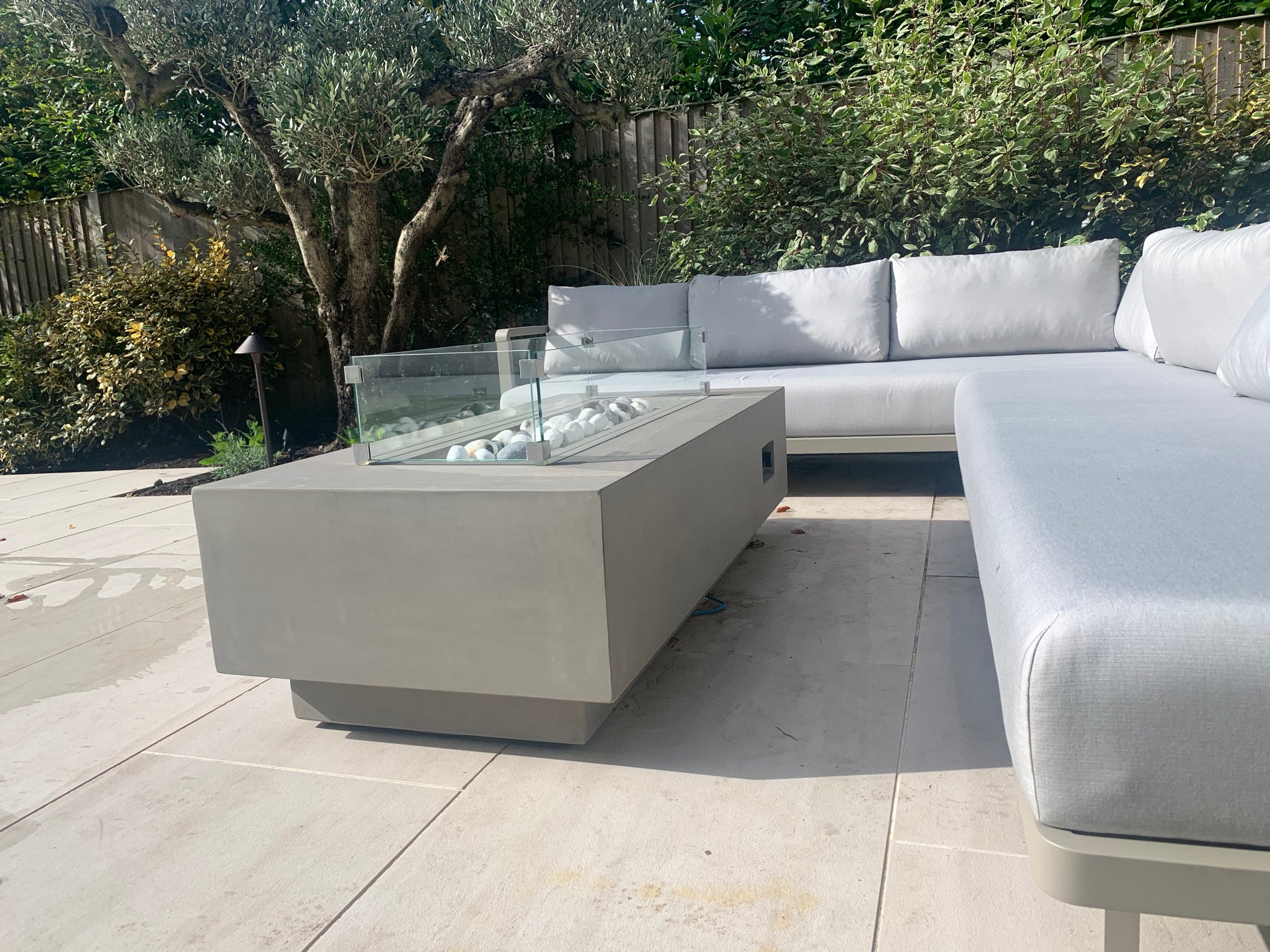 gas fire table in grey surrounded by soft garden furnishings on decking area