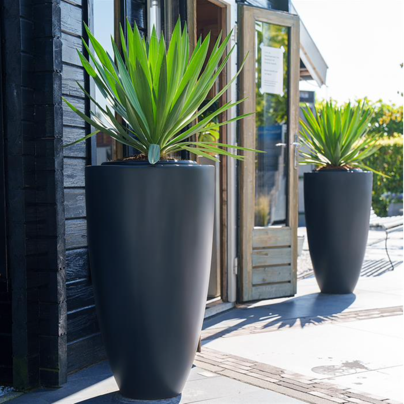 two tall round black garden pots