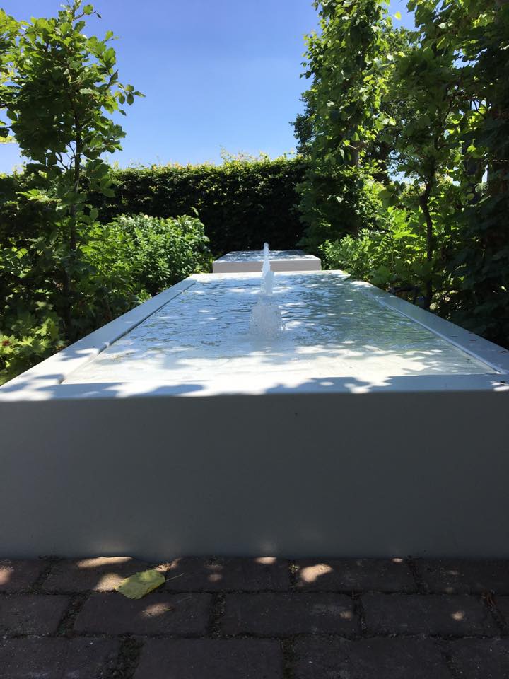 long rectangular white water table filled with water with fountains